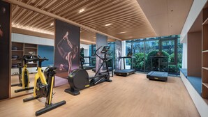 A modern gym with wooden floors, various exercise equipment, large windows offering a view of greenery, and a ceiling with wooden slats. - Holiday Inn Express Beijing Zhongguancun Tech Park by IHG (Beijing)