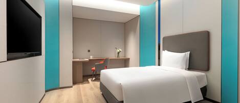 A modern hotel room with a bed, desk, and chair.