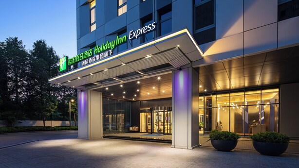 Ingresso di un hotel Holiday Inn Express, con un design moderno, ampie porte in vetro e una facciata ben illuminata.