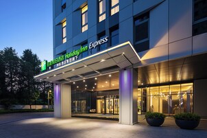 Eingang eines Holiday Inn Express Hotels mit modernem Design, großen Glasüren und einer gut beleuchteten Fassade.