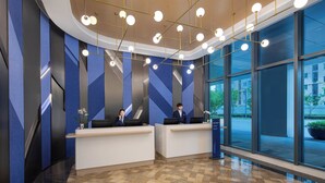 Un'area reception moderna con due scrivanie, un'ampia finestra che si affaccia sulla strada e un muro con motivo geometrico.