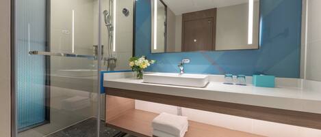 A modern bathroom with a glass shower enclosure, a sink with a mirror above, and a towel rack.