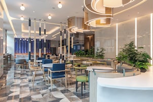 Eine moderne Hotelhalle mit einer Rezeption, Sitzbereichen und einem gemusterten Boden.