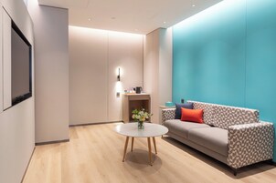 Ein modernes Wohnzimmer mit einer Couch, einem Couchtisch und einem an der Wand befestigten Fernseher.
