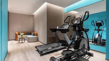 Ein moderner Fitnessraum mit Laufband, Crosstrainer und Ergometer.