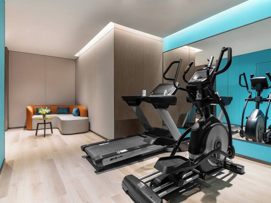 Ein moderner Fitnessraum mit Laufband, Crosstrainer und Ergometer.
