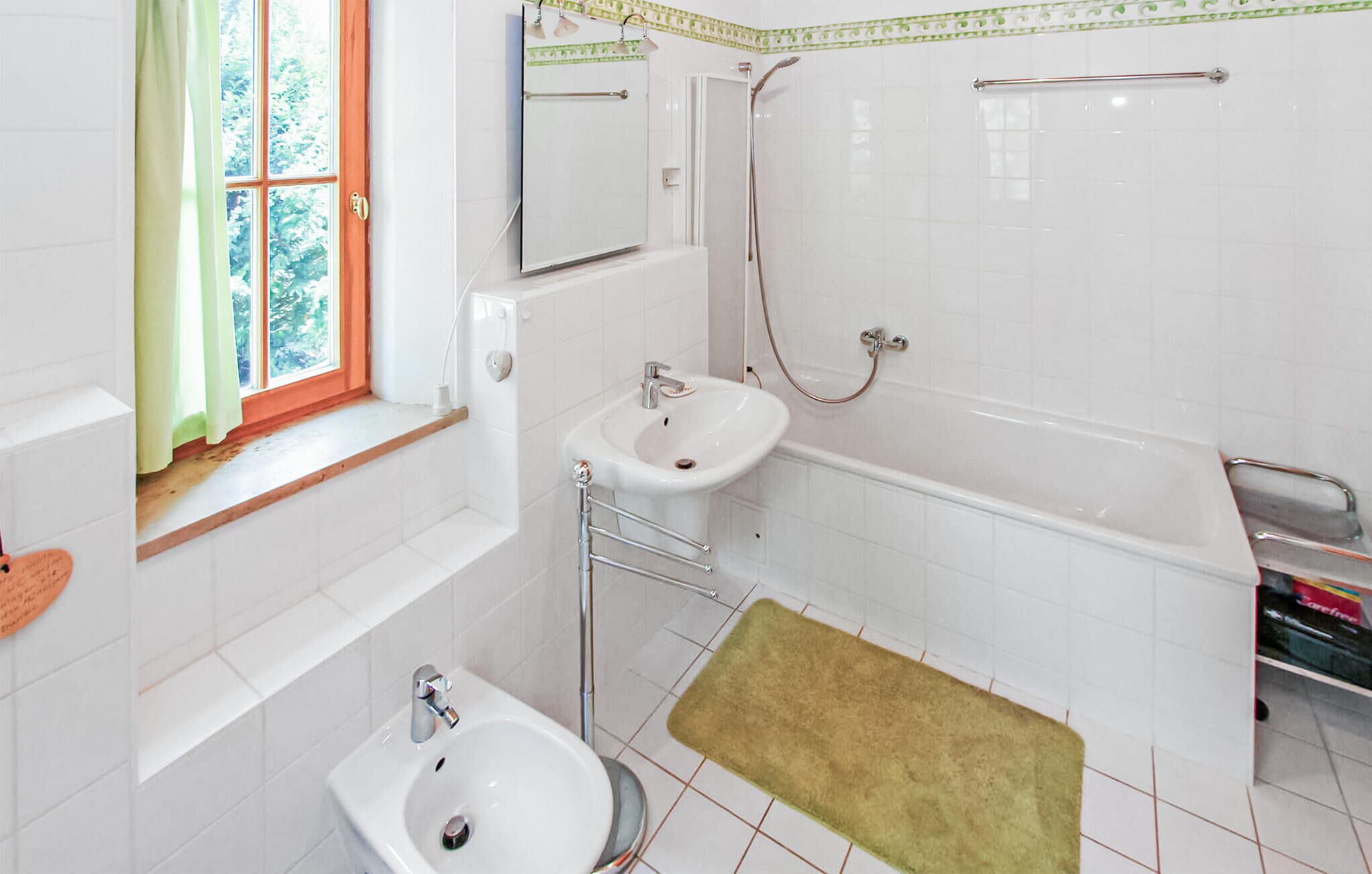 A small, clean bathroom with a sink, bidet, and bathtub.