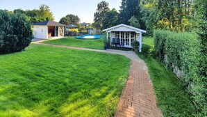 A backyard with a swimming pool, a covered patio, and a brick pathway. - Ferienwohnung Neppermin/Usedom (Neppermin/Usedom)