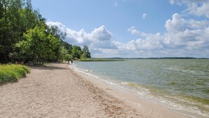 A sandy beach with a calm water body, surrounded by greenery and trees. - Ferienwohnung Neppermin/Usedom (Neppermin/Usedom)