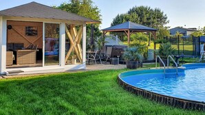 A backyard with a swimming pool, a covered seating area, and a patio with outdoor furniture. - Ferienwohnung Neppermin/Usedom (Neppermin/Usedom)