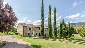 A stone building with a tiled roof, surrounded by a well-maintained lawn and tall cypress trees. - Il Casale di John - Discover Authentic Italy (Umbertide)