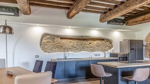 A modern kitchen with a stone accent wall, a bar area, and a dining space with bar stools. - Il Casale di John - Discover Authentic Italy (Umbertide)