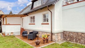 A house with a patio, outdoor furniture, and a stone wall.