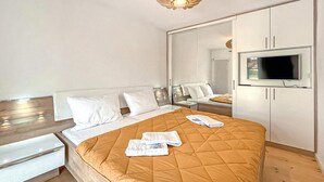 A modern hotel room with a large bed, a TV, and a wardrobe.