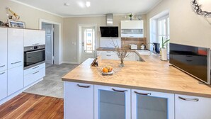 A modern kitchen with white cabinets, a wooden countertop, and a built-in oven.