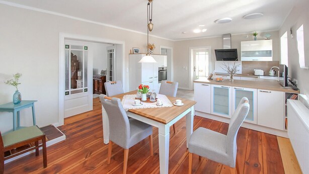 A modern kitchen with white cabinets, a wooden countertop, and a built-in oven.