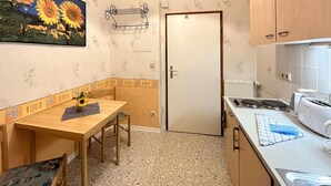 Pieni, käytännöllinen keittiö, jossa on ruokapöytä, tuolit, patteri ja leivänpaahdin.