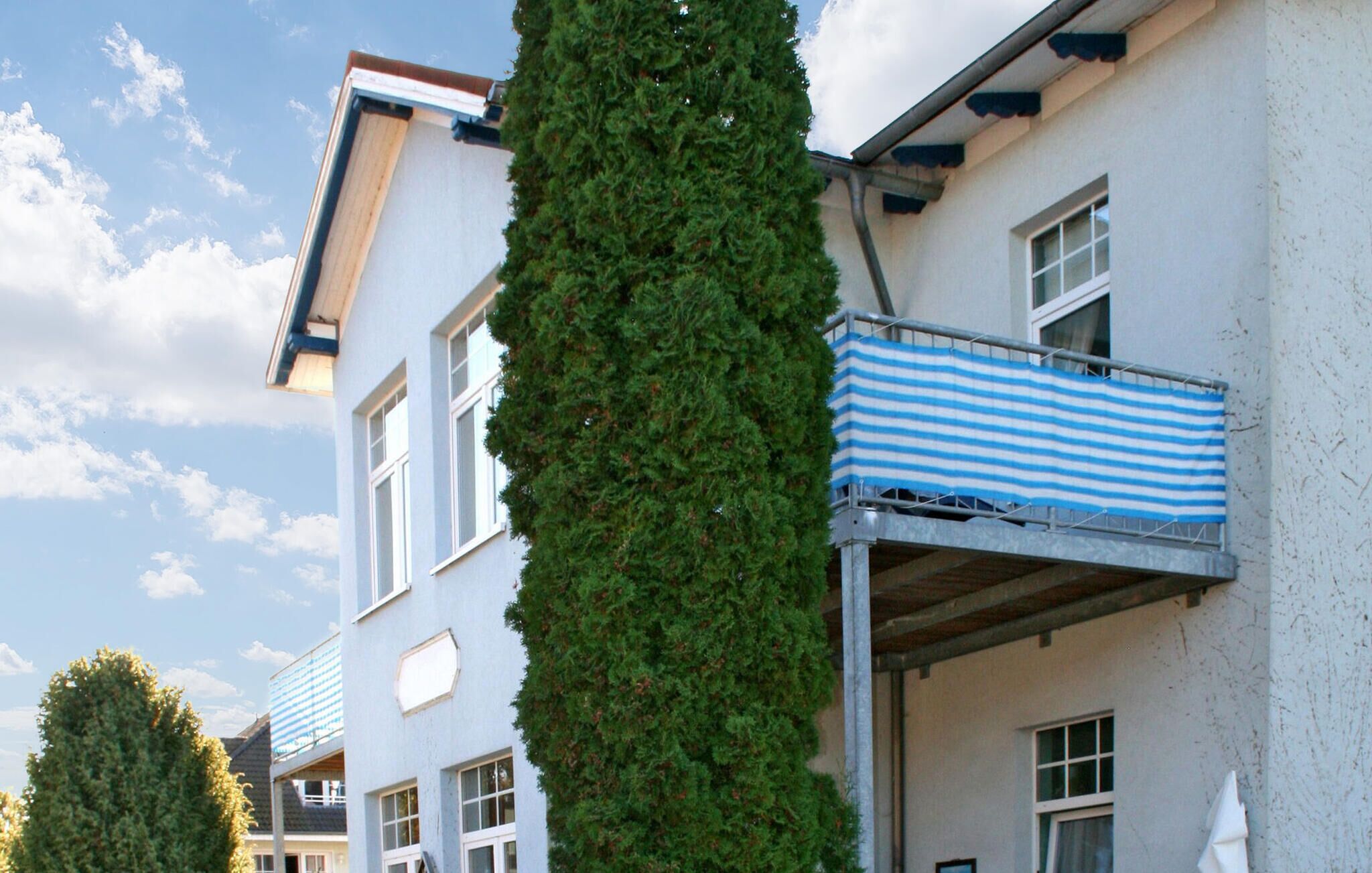 A multi-story building with a balcony featuring a blue and white striped awning.