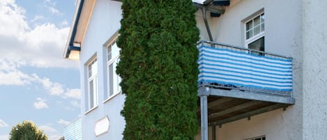 A multi-story building with a balcony featuring a blue and white striped awning.