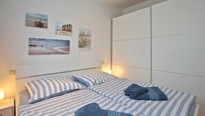 Un dormitorio con dos camas, ropa de cama a rayas y una obra de arte en la pared.