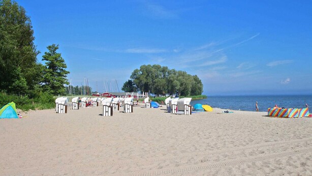 Una playa con filas de cabañas de playa y una vista despejada del mar.