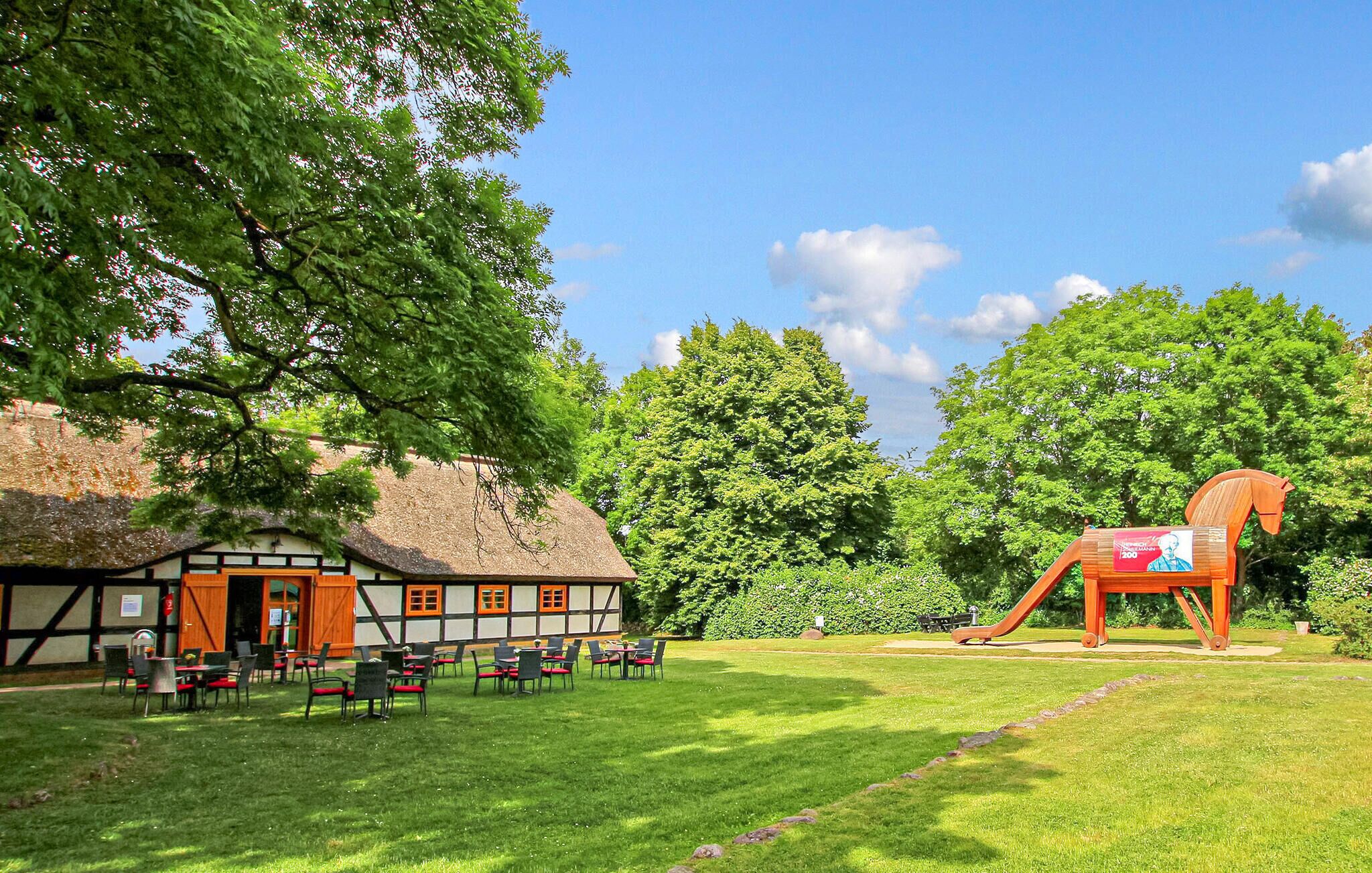 A traditional building with a thatched roof, outdoor seating area, and a wooden horse sculpture.