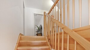 Un escalier en bois, doté d’une rampe, mène à une porte.