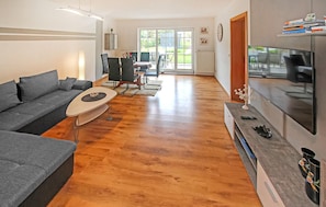 A modern living room with a grey sofa, a coffee table, and a TV on a stand. - Ferienhaus Saal Bartelshagen (Saal OT Bartelshagen I)