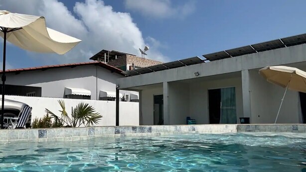 A swimming pool with clear water, a white building with a flat roof, and a satellite dish. - Solaris Serrambi Flats (Ipojuca)
