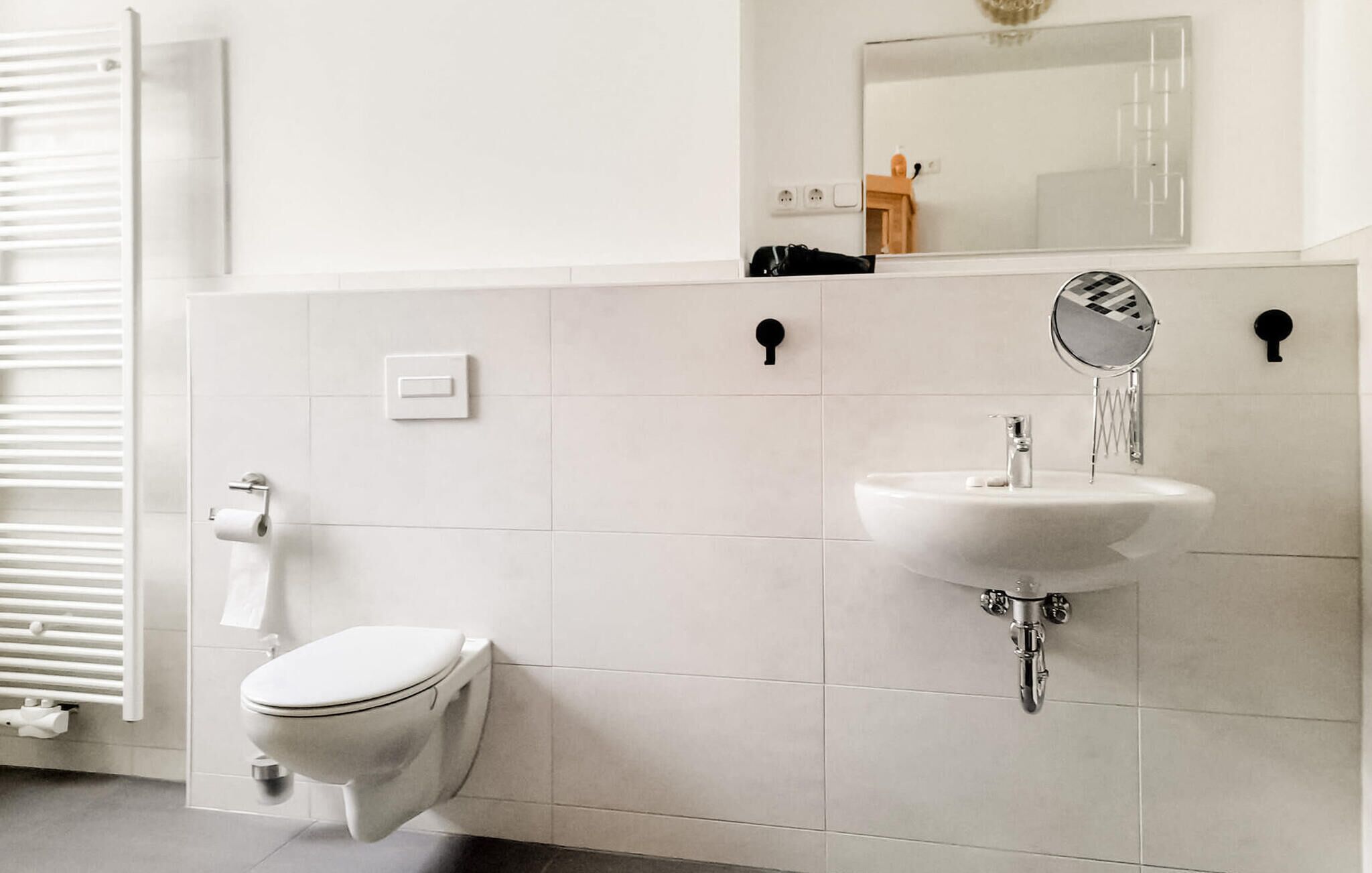 A modern bathroom with a toilet, a sink with a mirror, and a towel dispenser.