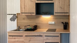 Une cuisine compacte dotée de meubles en bois, d’un four encastré, d’un évier et d’un égouttoir à vaisselle.
