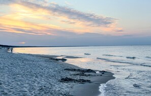 Een strand met een rustige zee en een ondergaande zon.