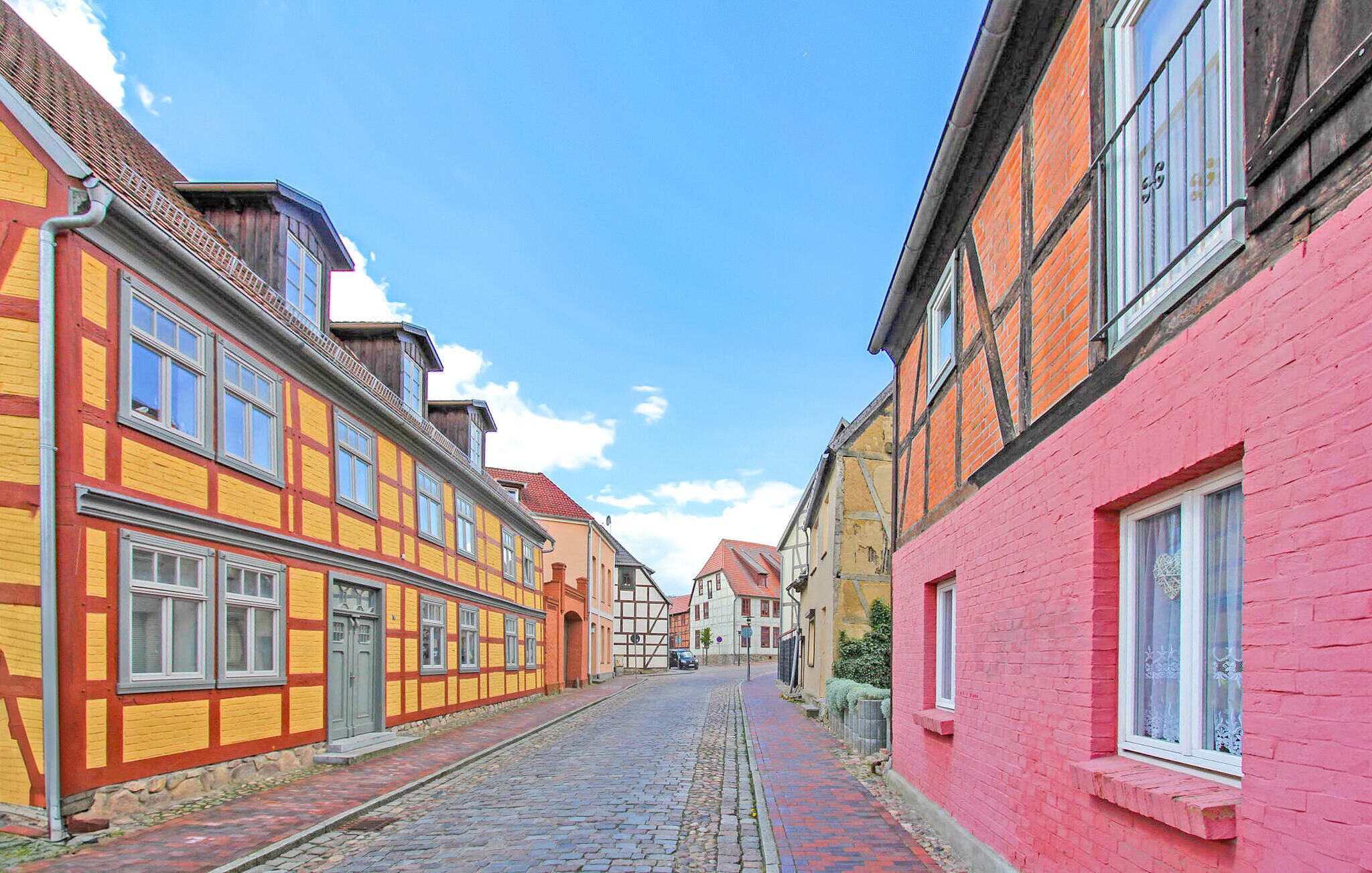 Une ruelle étroite pavée, bordée de bâtiments aux façades colorées à pans de bois.