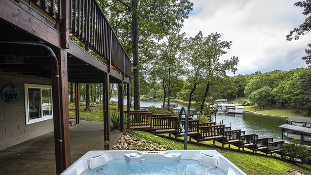 Ein Whirlpool mit einer Holzterrasse und Blick auf einen See und eine Anlegestelle.