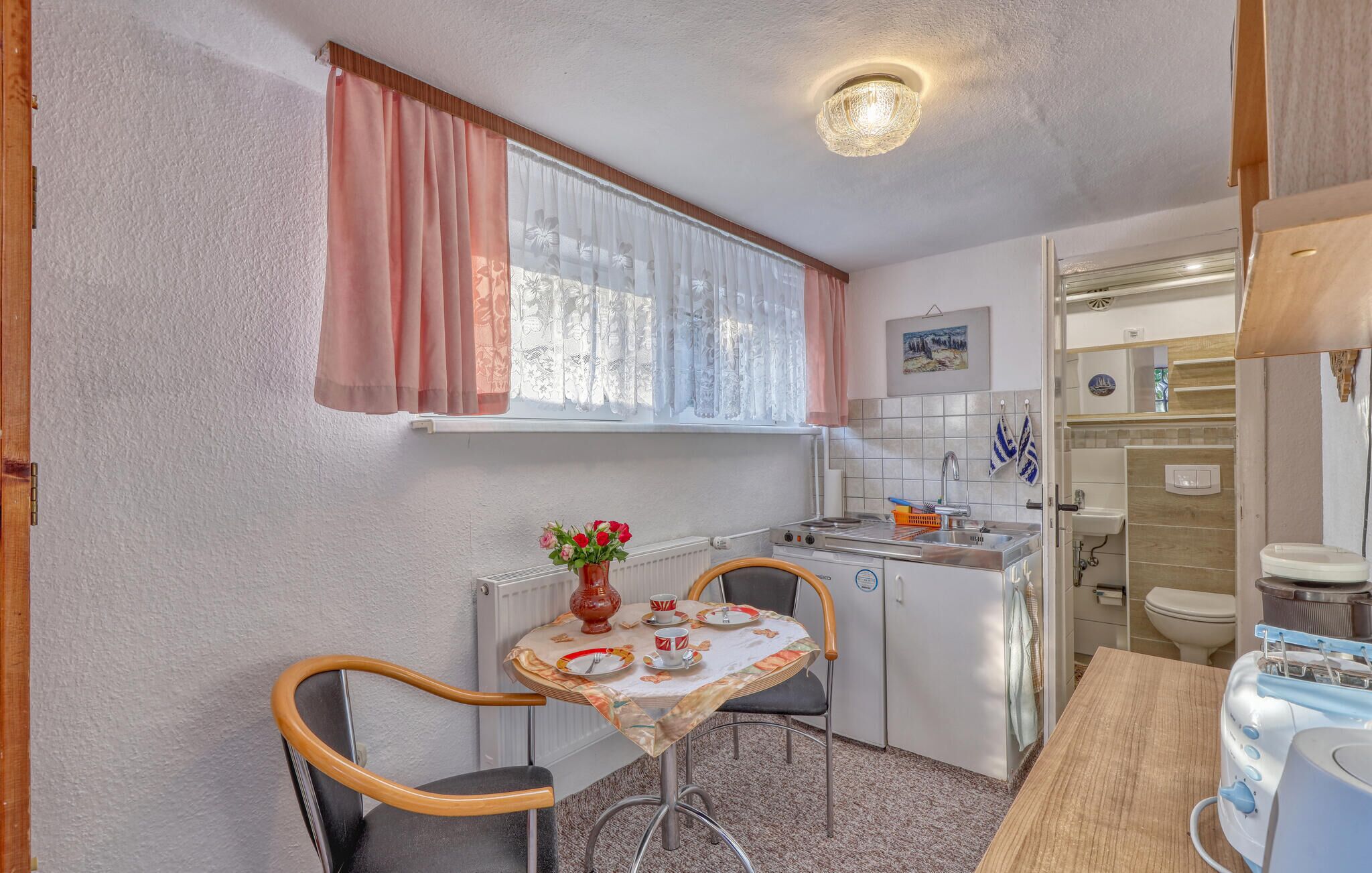 A compact kitchen with a dining table, chairs, a stove, and a sink.
