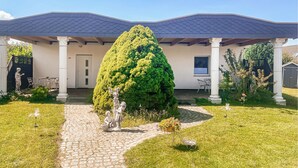 Een huis met twee verdiepingen, een overdekte veranda, een pad van stenen naar de ingang en een verzorgd gazon.
