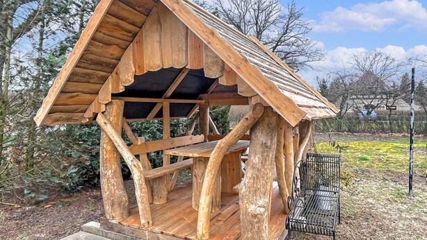 Une structure en bois dotée d’un toit incliné et d’un banc à l’extérieur.