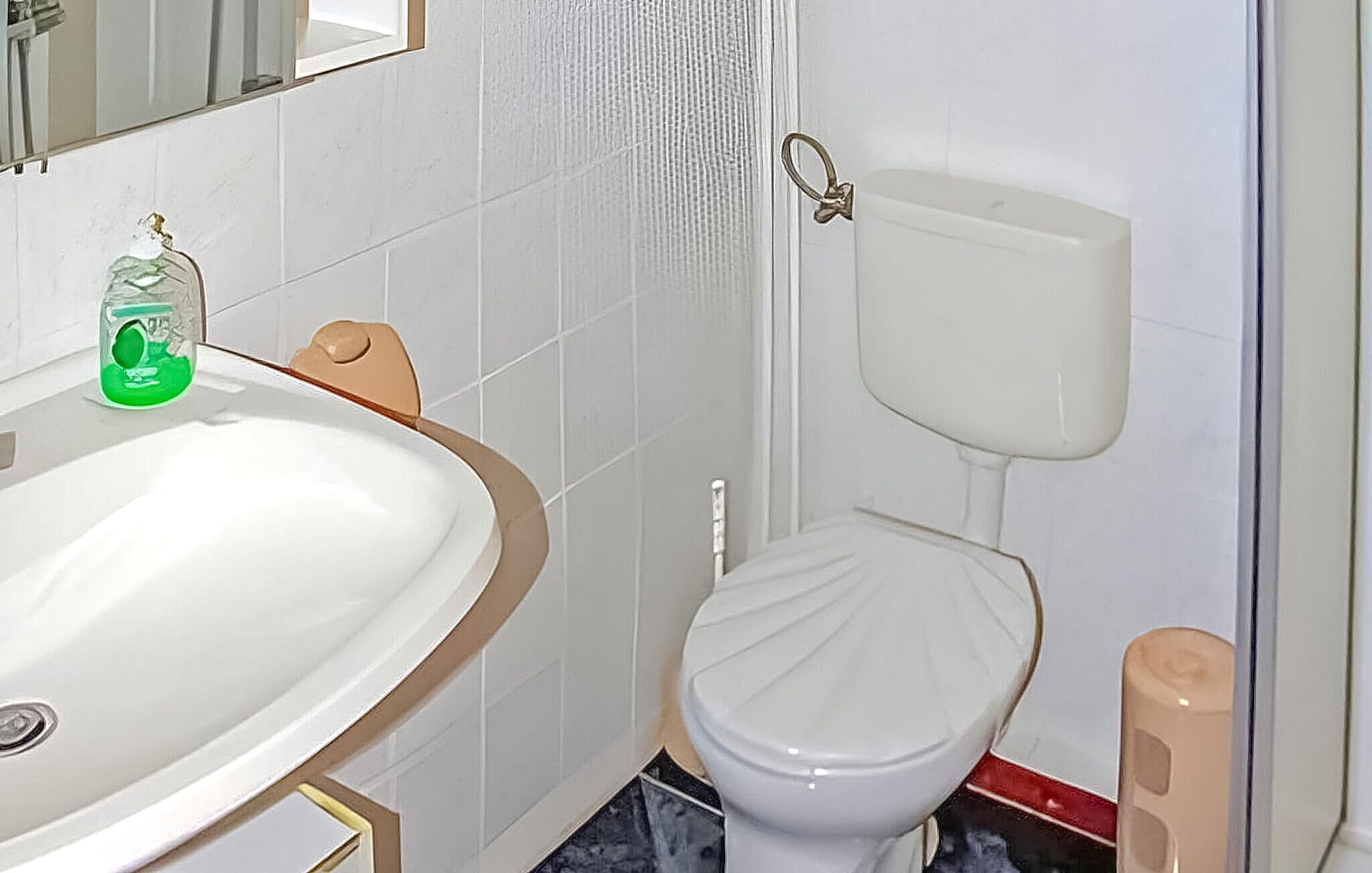 Un baño con lavamanos, inodoro y espejo blancos.