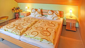 Ein Hotelzimmer mit einem Bett, zwei Nachttischen, einer Lampe, einer Vase mit Blumen und einem Sessel.
