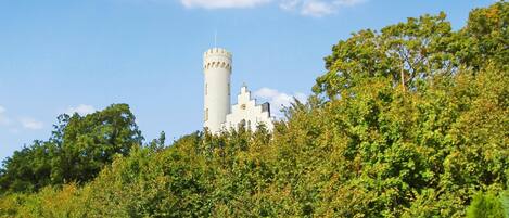 A castle-like structure with a prominent tower, surrounded by dense green foliage.