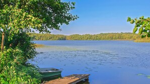 A calm lake with a wooden dock extending into the water, surrounded by lush greenery and a distant forested shoreline. - Amazing apartment in Lychen (Lychen)