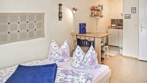 A bedroom with a bed, pillows, a desk, and a kitchenette. - Amazing apartment in Lychen (Lychen)