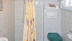 A bathroom with a shower curtain, a toilet, and a towel rack with towels. - Amazing apartment in Lychen (Lychen)