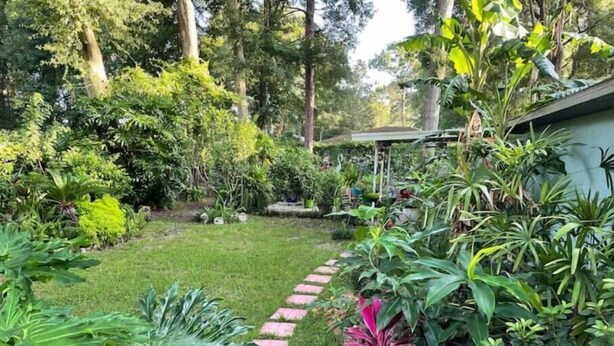 A garden with a paved path, various plants, and trees. - Retro Style Camper. SW Ocala-Near WEC-Comfy Bed (Ocala)