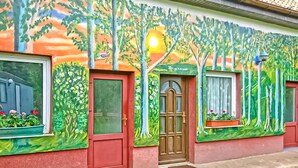 A building with a mural of trees and flowers, a red door, and windows with flower boxes. - 1 bedroom beautiful home in Luckow (Luckow)
