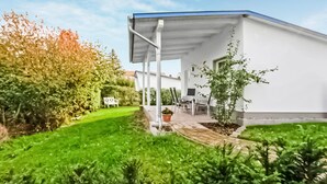 Een modern huis met een overdekt terras, een gazon en een tuin.