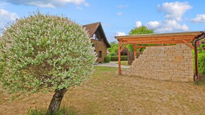Une maison avec une pergola en bois et un mur en pierre dans le jardin arrière.