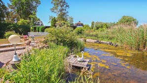 A serene outdoor area with a pond, a wooden dock, and a swan sculpture.