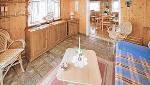 A wooden interior with a dining area, a table with a candle, and wicker furniture.