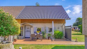 Ein zweistöckiges Haus mit Ziegeldach, einer Holzveranda und einer Ziegelterrasse.